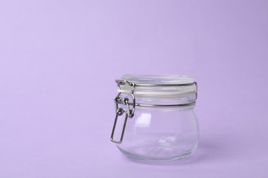 Photo of Closed empty glass jar on lilac background