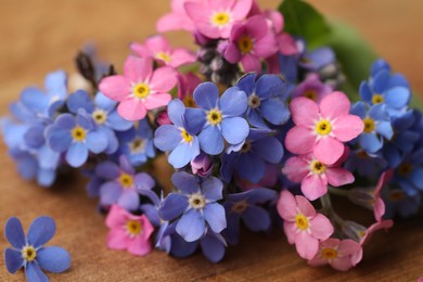 Photo of Beautiful fresh Forget-me-not flowers on wooden table, closeup