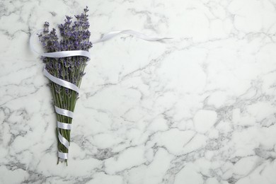 Photo of Beautiful lavender flowers with ribbon on white marble table, top view. Space for text