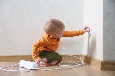 Little child playing with electrical socket and power strip plug at home. Dangerous situation