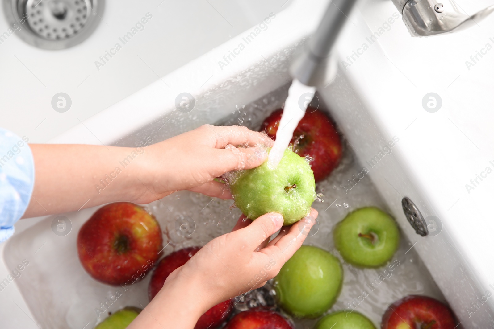 Photo of Woman washing fresh apples in kitchen sink, closeup