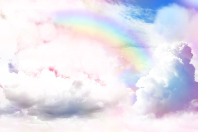 Image of Fantasy world. Beautiful rainbow in sky with fluffy clouds 