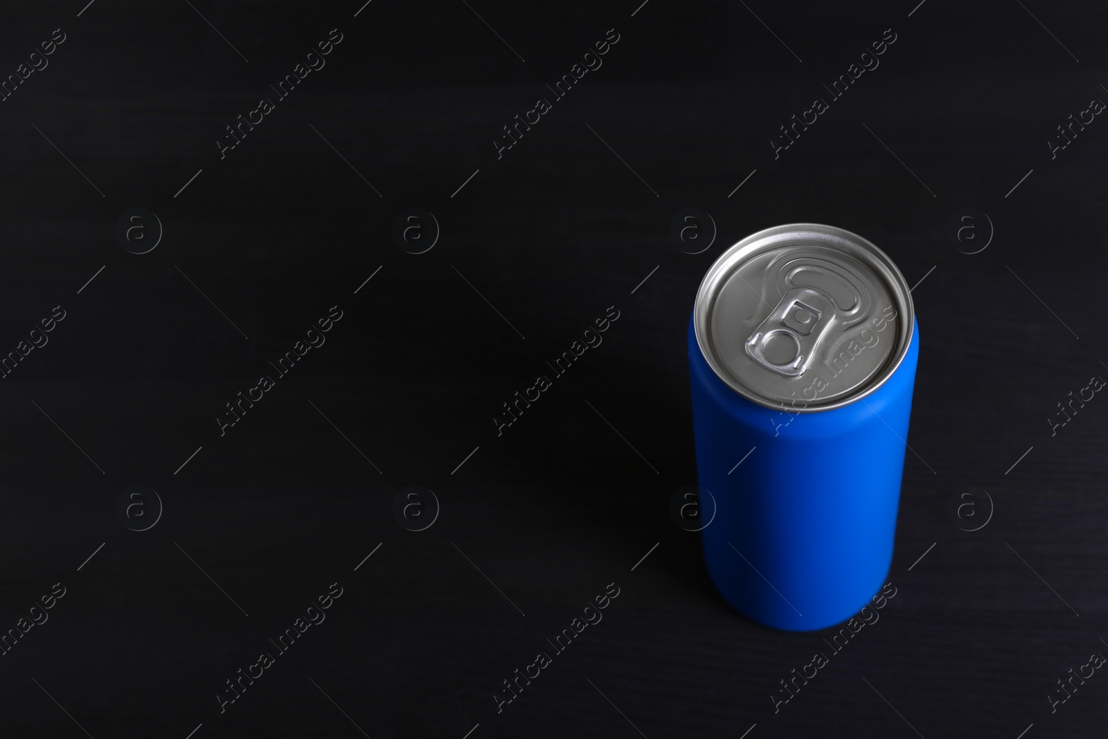 Photo of Energy drink in blue can on black wooden table, space for text