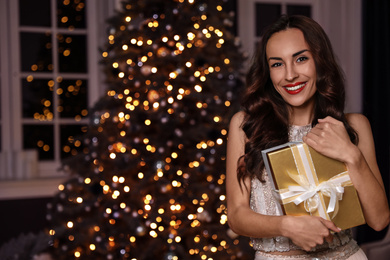 Beautiful woman with gift box in decorated room. Christmas celebration
