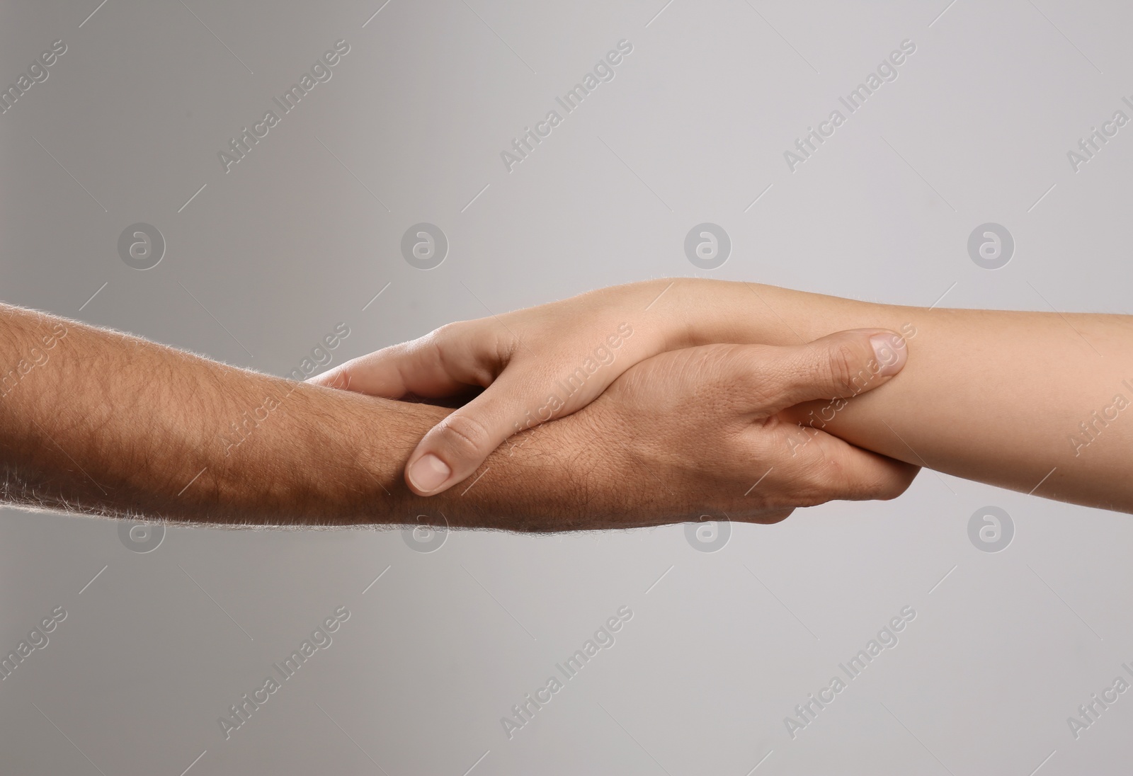 Photo of Man and woman holding hands on grey background, closeup. Help and support concept