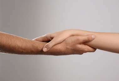 Photo of Man and woman holding hands on grey background, closeup. Help and support concept