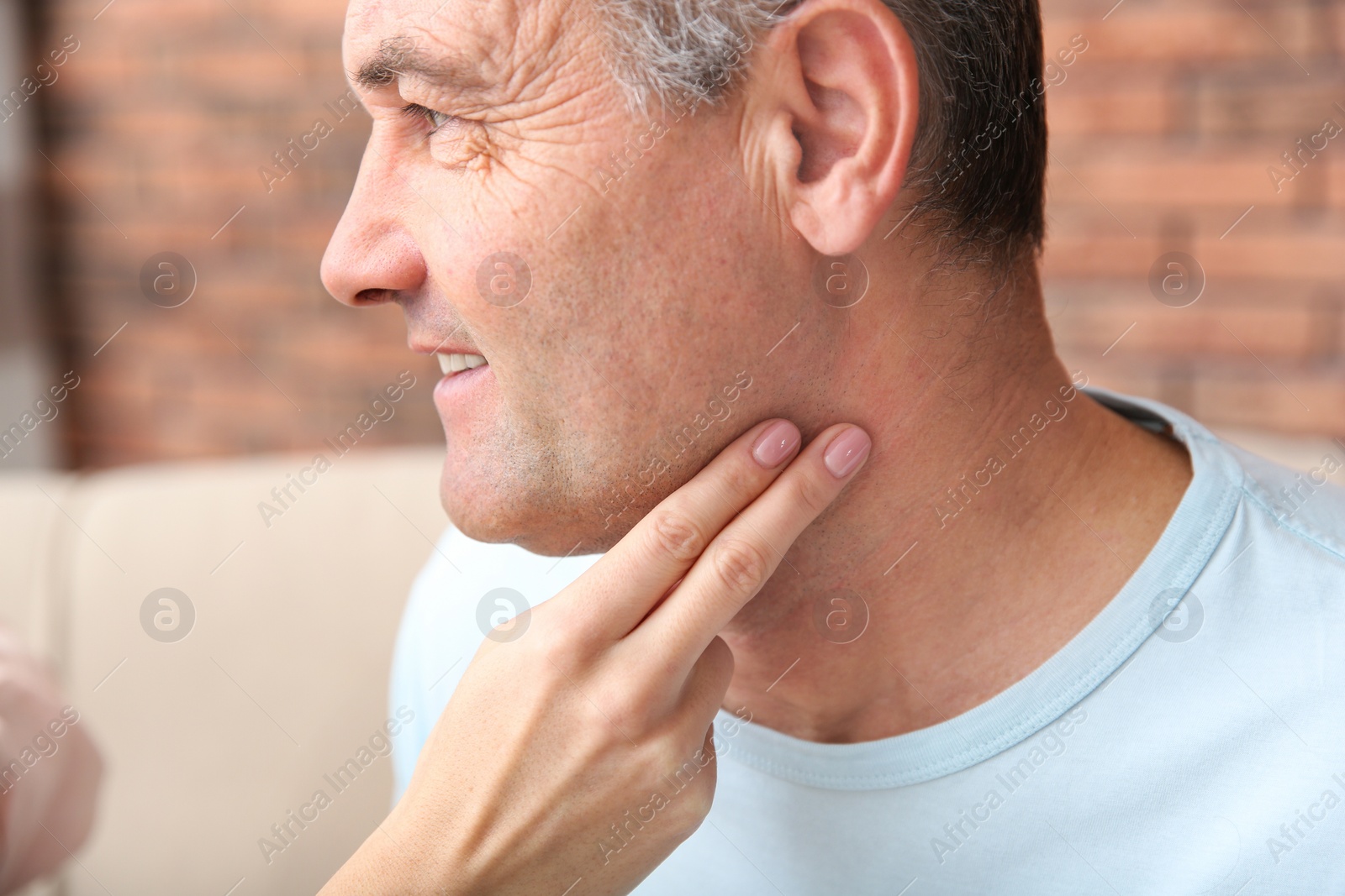 Photo of Young woman checking mature man's pulse with fingers indoors