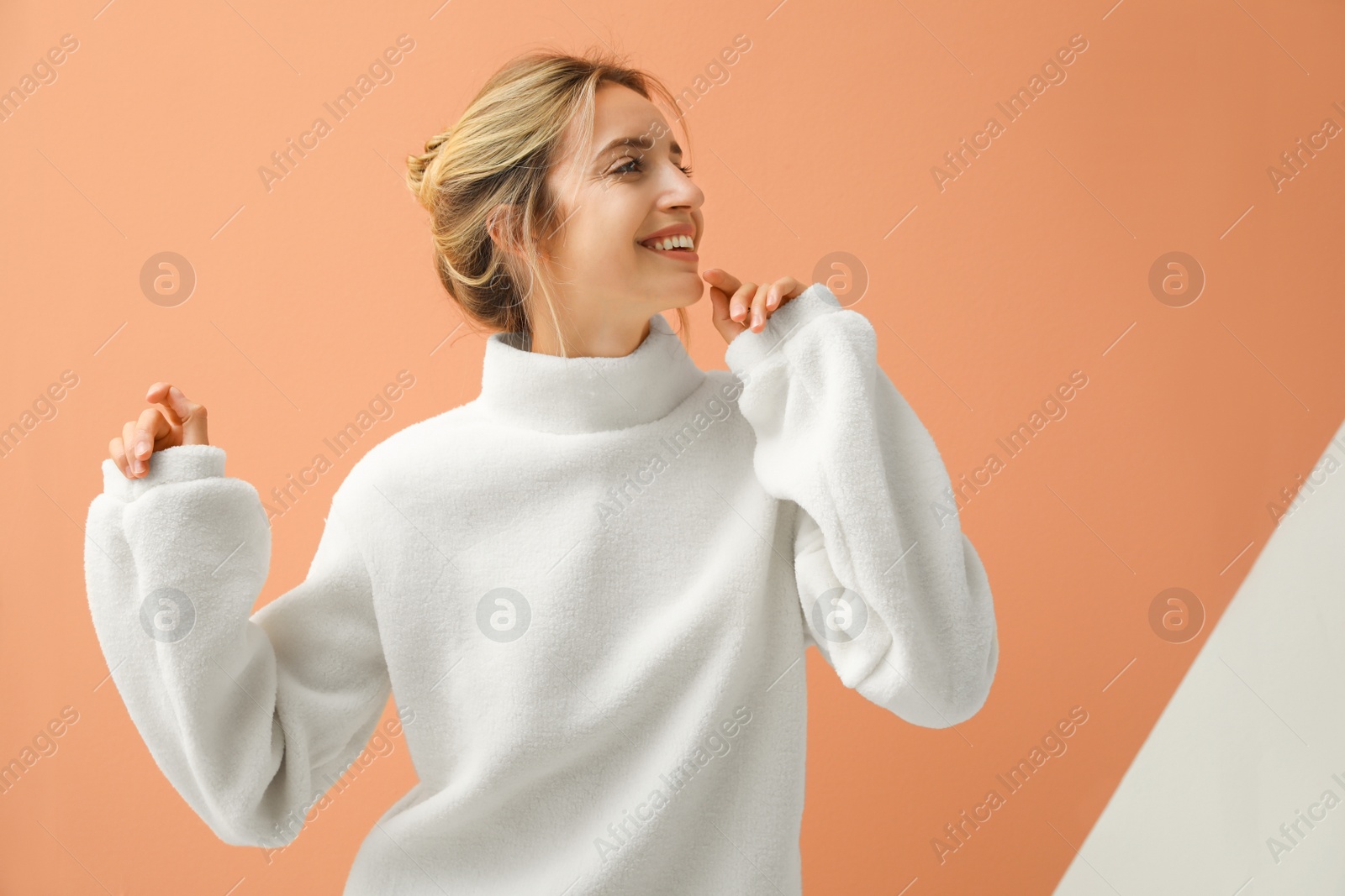 Photo of Beautiful young woman wearing knitted sweater on color background