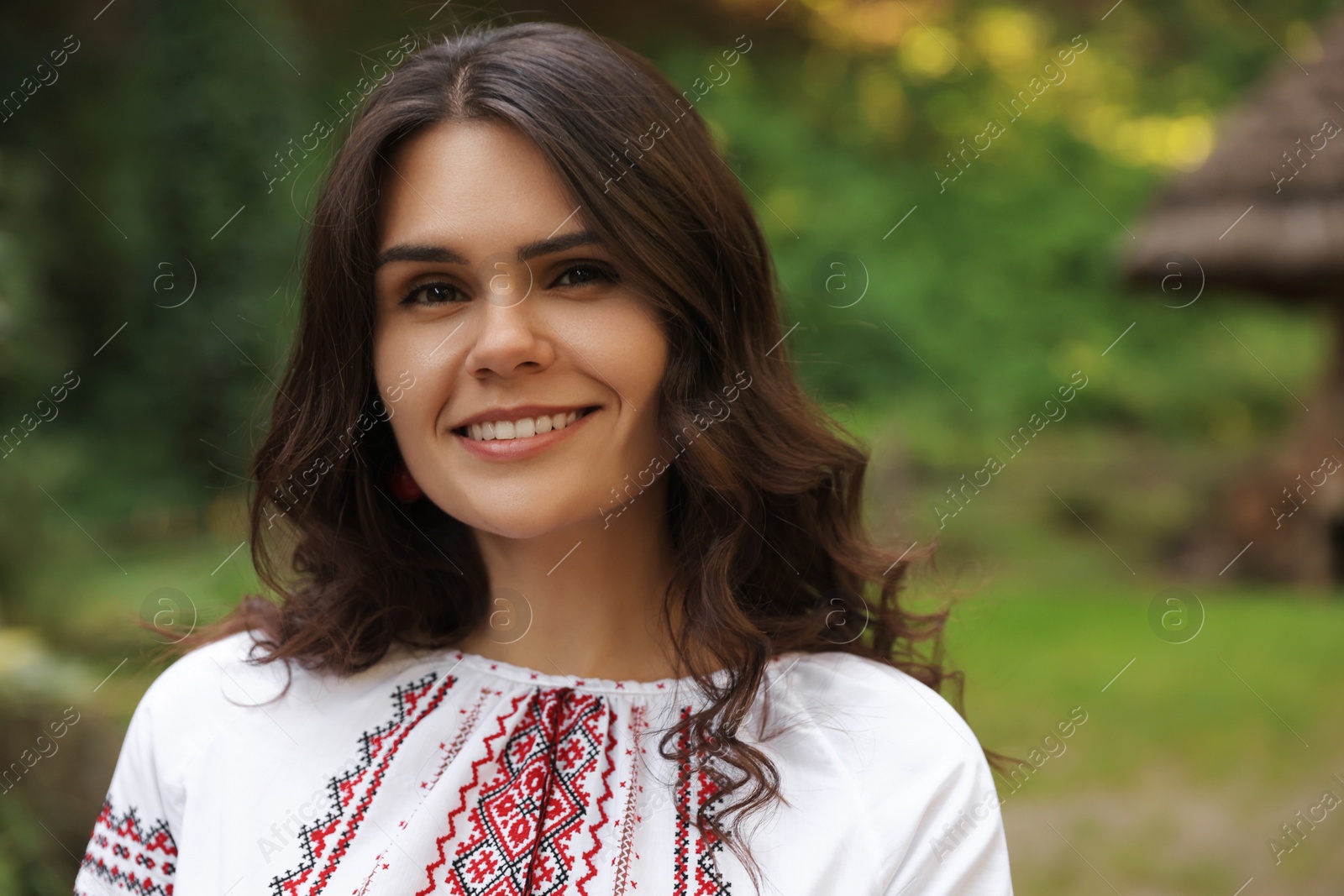 Photo of Beautiful woman wearing embroidered shirt in village, space for text. Ukrainian national clothes