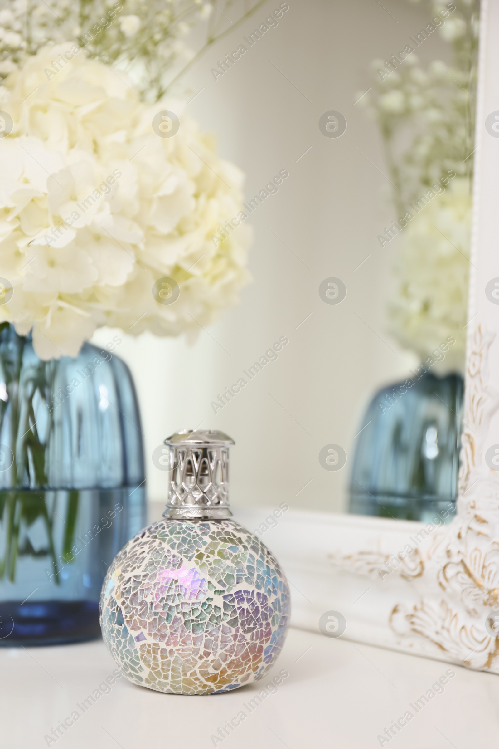 Photo of Stylish catalytic lamp with beautiful bouquet on white table near mirror. Cozy interior