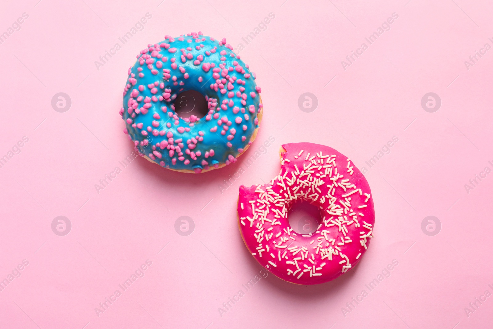 Photo of Delicious glazed doughnuts on color background, top view