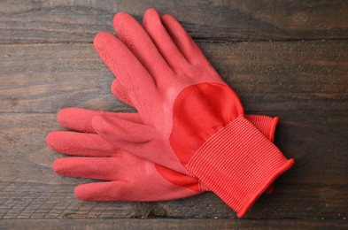 Pair of red gardening gloves on wooden table, top view