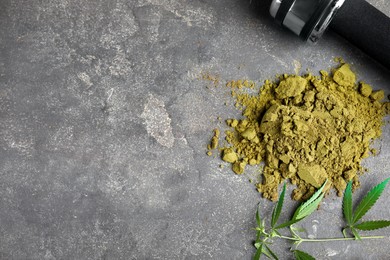 Hemp protein powder, fresh leaves and dumbbell on grey table, flat lay. Space for text