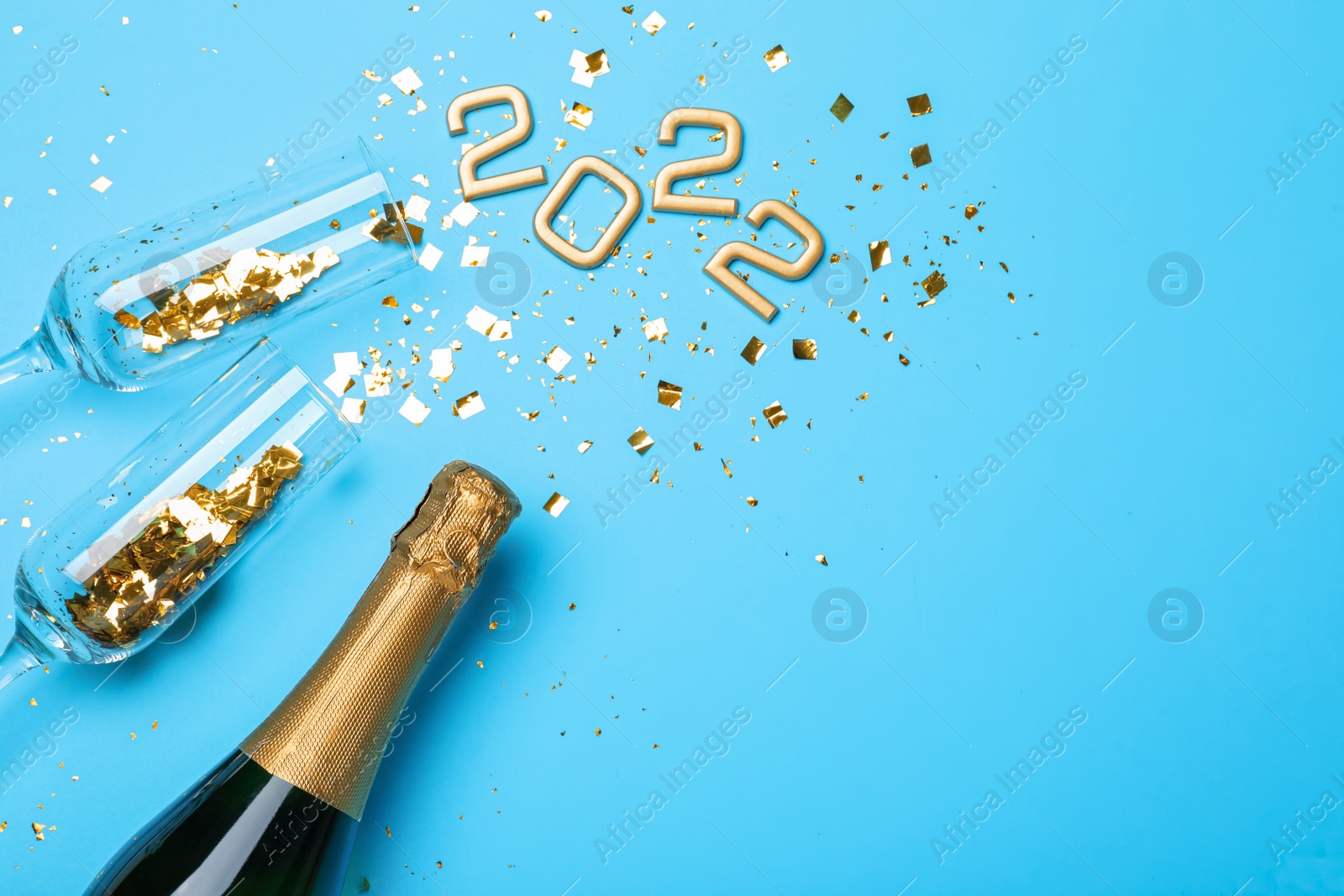 Photo of Happy New Year 2022! Flat lay composition with bottle of sparkling wine on light blue background, space for text