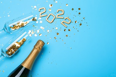 Photo of Happy New Year 2022! Flat lay composition with bottle of sparkling wine on light blue background, space for text