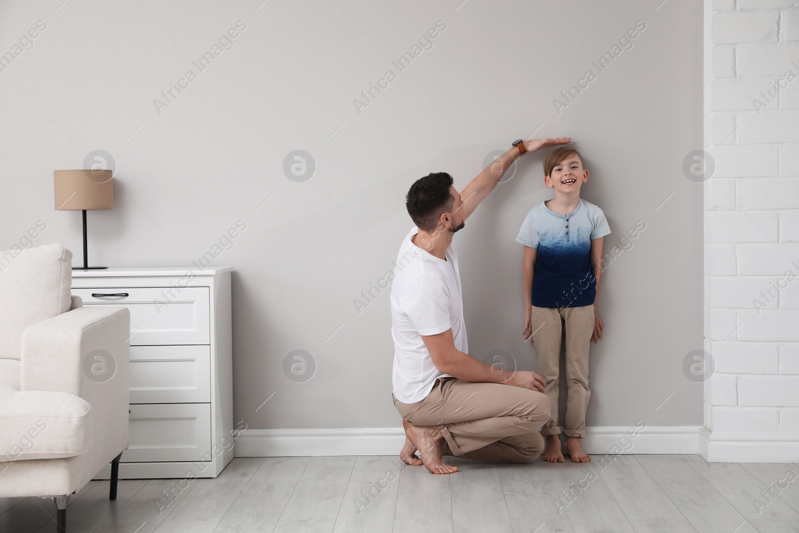 Photo of Father measuring height of his son near wall at home