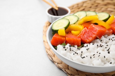 Delicious poke bowl with salmon, rice and vegetables on white table, closeup. Space for text