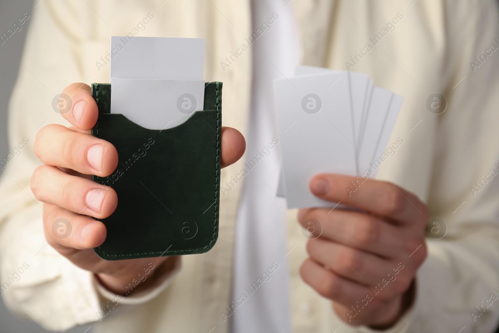 Photo of Man holding leather business card holder with blank cards, closeup