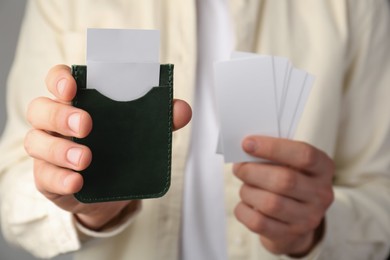 Man holding leather business card holder with blank cards, closeup