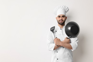 Photo of Professional chef with wok and spatula on white background