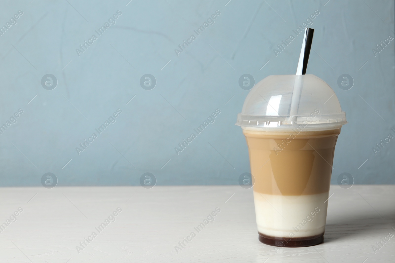 Photo of Plastic cup of tasty caramel macchiato on table, space for text