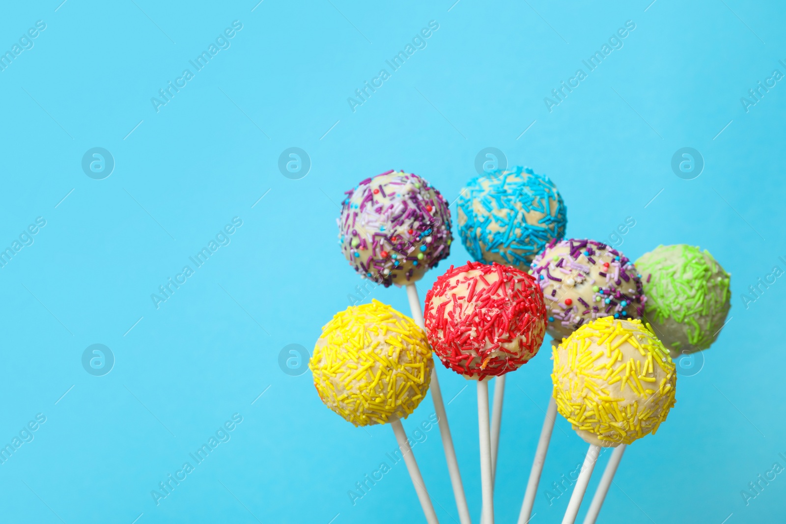 Photo of Yummy bright cake pops on color background. Space for text