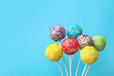 Photo of Yummy bright cake pops on color background. Space for text