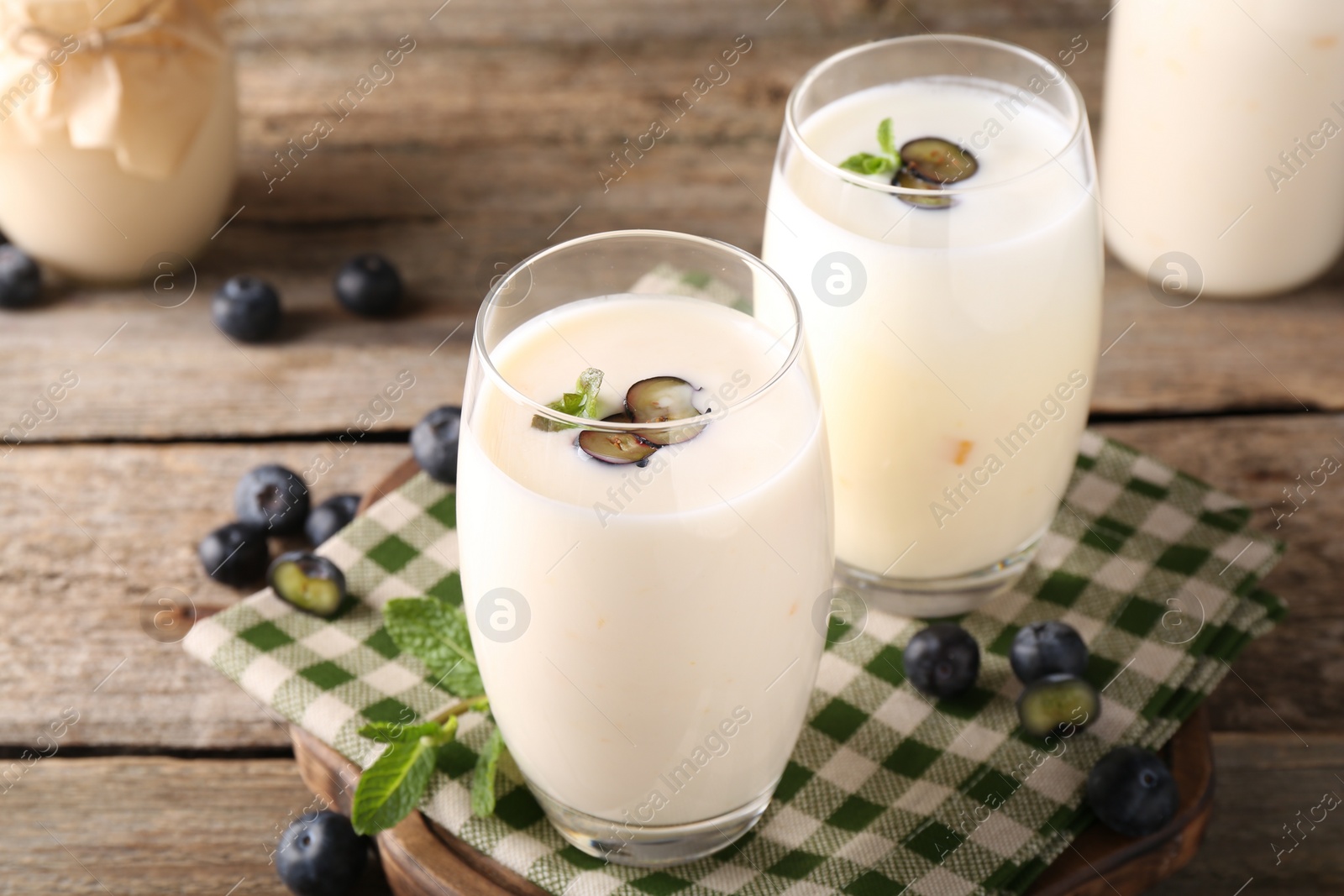 Photo of Tasty yogurt in glasses and blueberries on wooden table, closeup