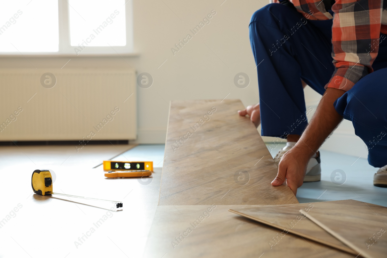 Photo of Professional worker installing new parquet flooring indoors, closeup