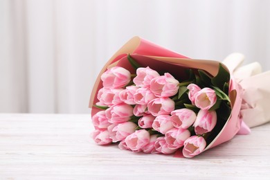 Beautiful bouquet of fresh pink tulips on white wooden table indoors. Space for text