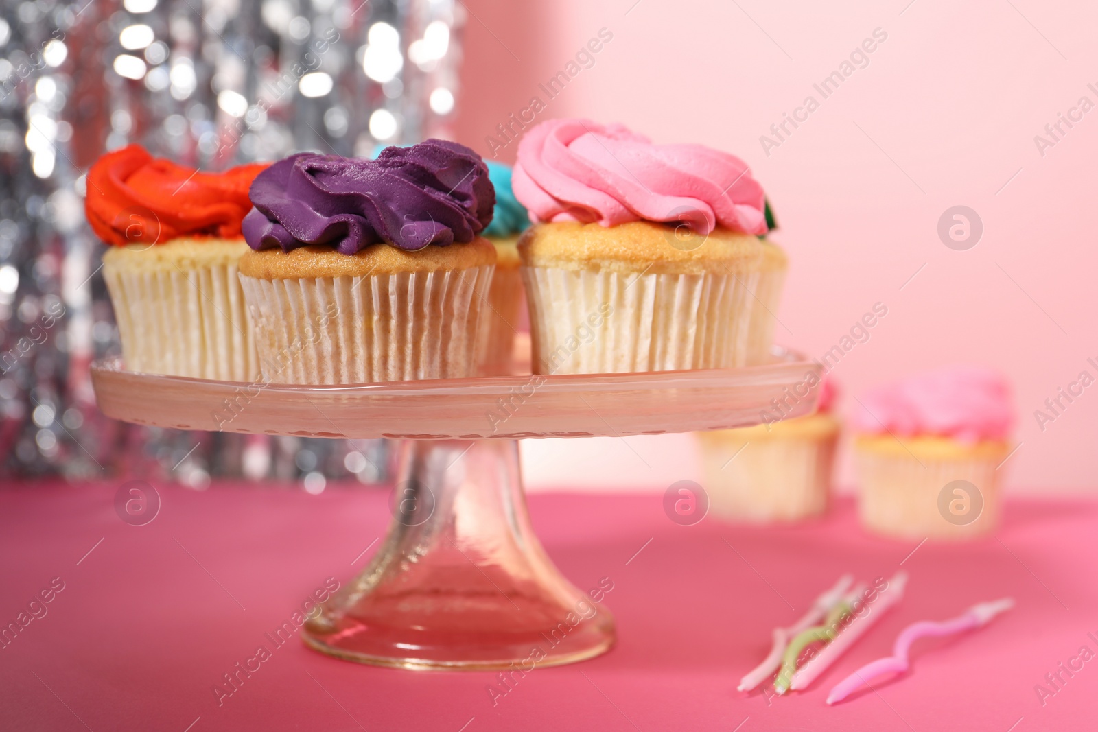 Photo of Delicious cupcakes with bright cream and candles on pink table