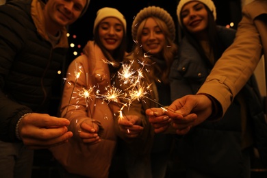 Photo of Grouppeople holding burning sparklers, focus on hands