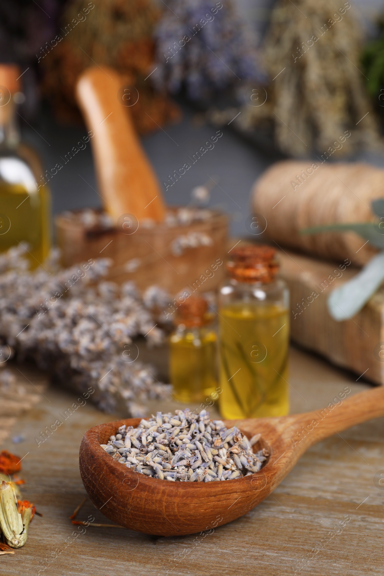Photo of Spoon with lavender flowers on wooden table, closeup. Medicinal herbs
