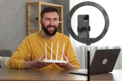 Smiling technology blogger recording video review about WI-FI router at home