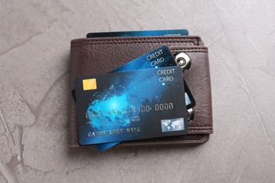 Photo of Leather wallet with credit cards on grey textured table, top view