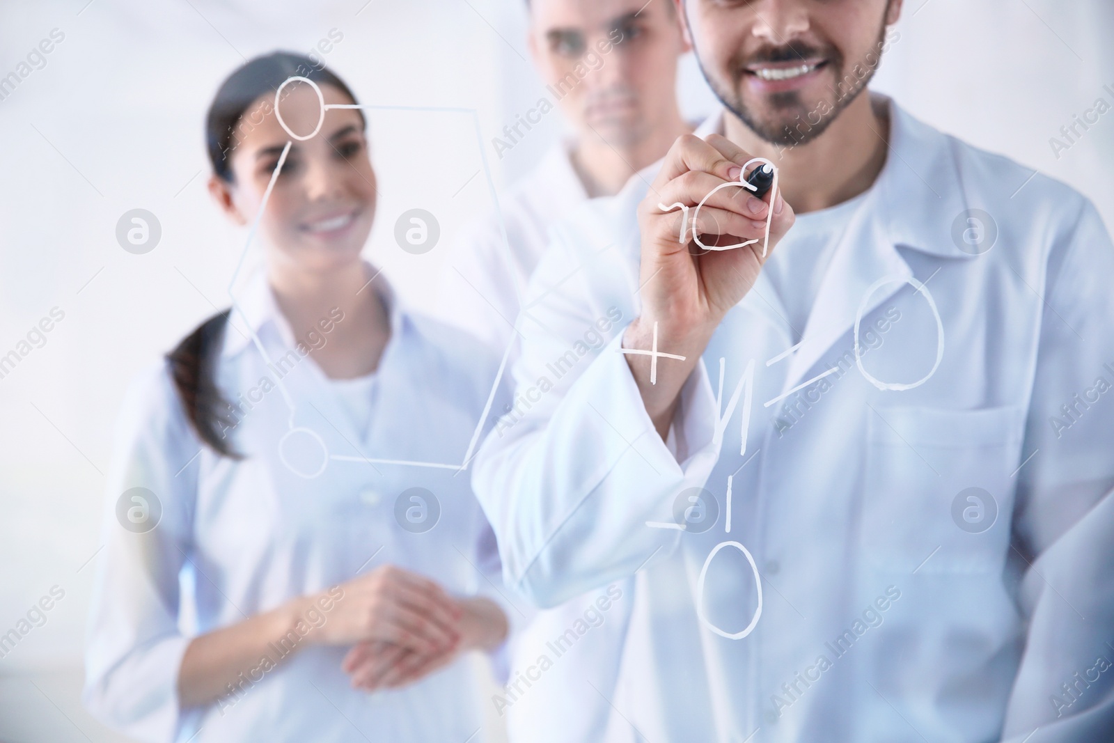 Photo of Medical students writing chemical formula on glass whiteboard in laboratory