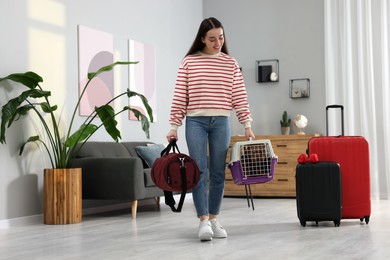 Travel with pet. Smiling woman holding carrier with dog and bag at home