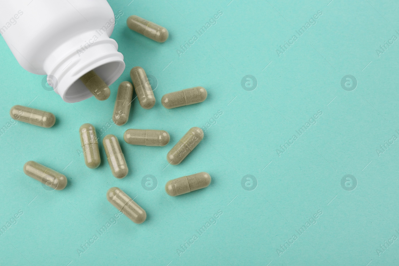 Photo of Bottle and vitamin capsules on turquoise background, top view. Space for text