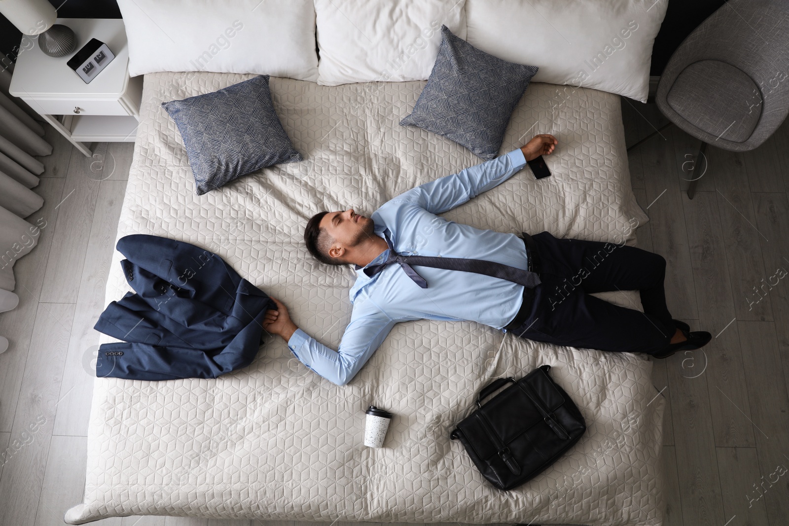 Photo of Exhausted businessman in office wear sleeping on bed at home after work, above view