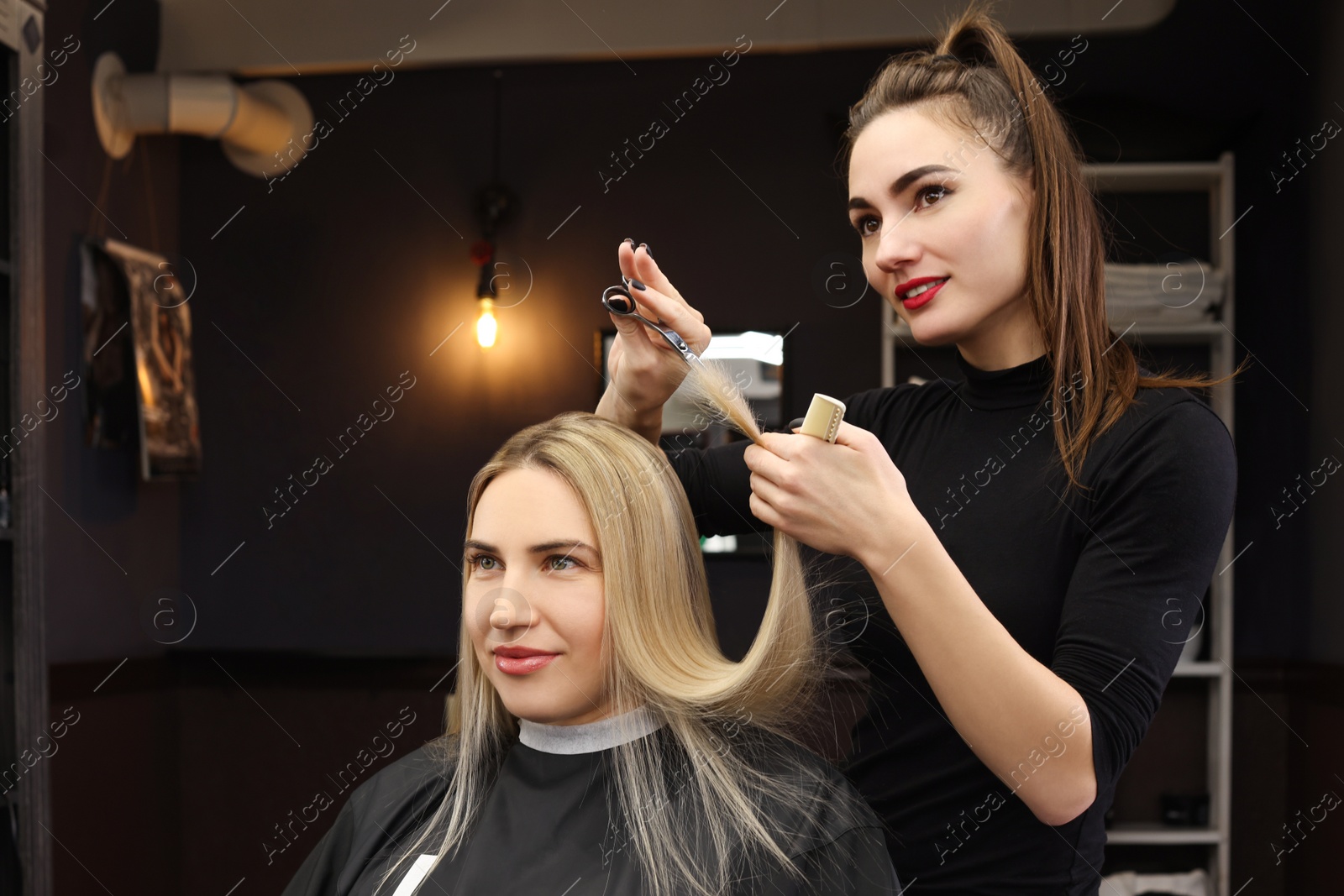 Photo of Professional hairdresser cutting woman's hair in salon