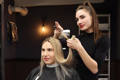 Photo of Professional hairdresser cutting woman's hair in salon