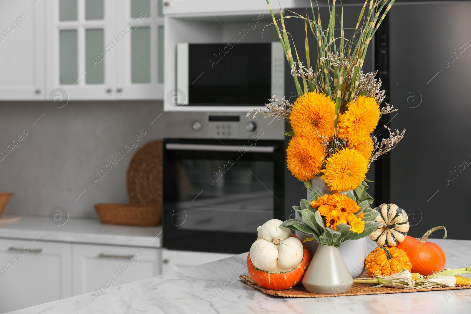 Photo of Beautiful autumn bouquets and pumpkins on marble table in kitchen