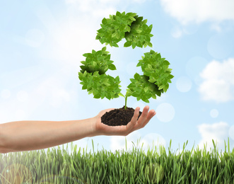 Man holding fertile soil in hand and recycling symbol, closeup 