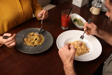 Lovely young couple having pasta carbonara for dinner at restaurant