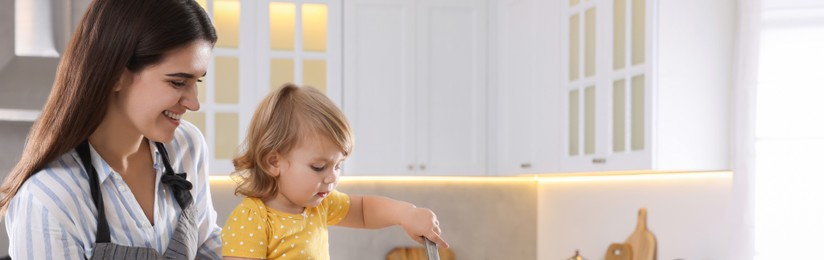 Mother and her little daughter cooking together in kitchen, space for text. Banner design