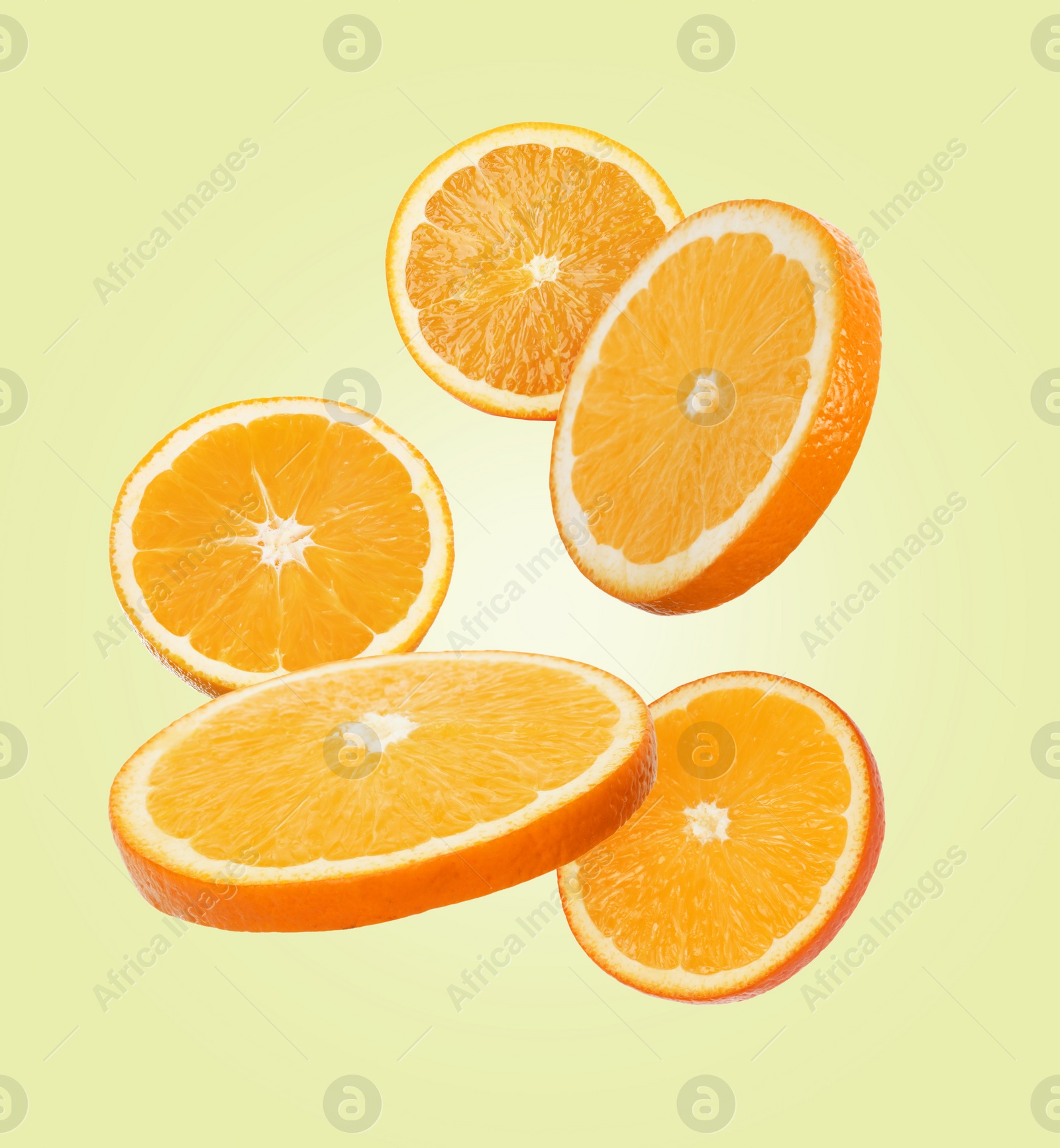 Image of Juicy orange slices flying on cream background