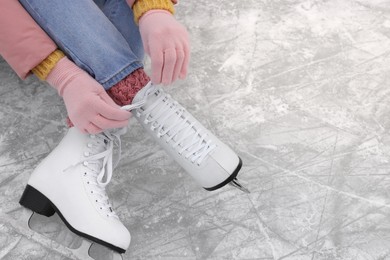 Photo of Woman lacing figure skates on ice, closeup. Space for text