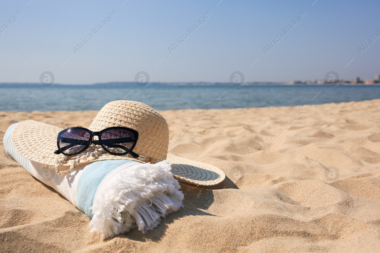 Photo of Straw hat, towel and sunglasses on sandy beach. Space for text