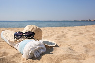 Photo of Straw hat, towel and sunglasses on sandy beach. Space for text