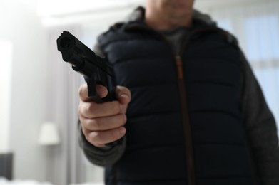 Photo of Dangerous criminal with gun in foreign house, selective focus. Armed robbery